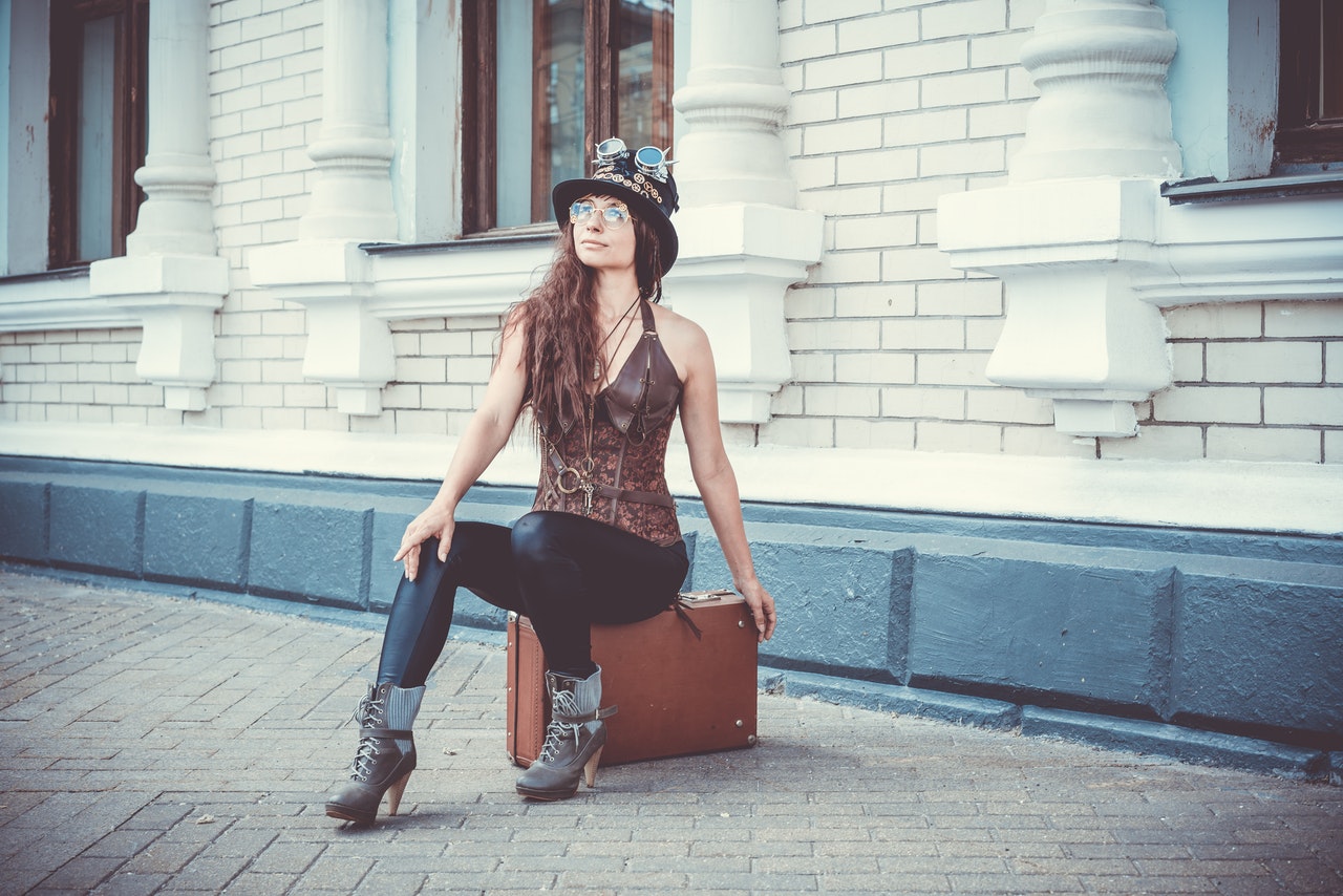 Woman is sitting on a suitcase wearing leather pants